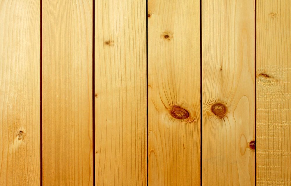 Close-up of vertical light wood boards with narrow gaps and dark knots