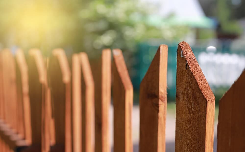 Close-up of new pointed wooden picket boards in warm sunlight