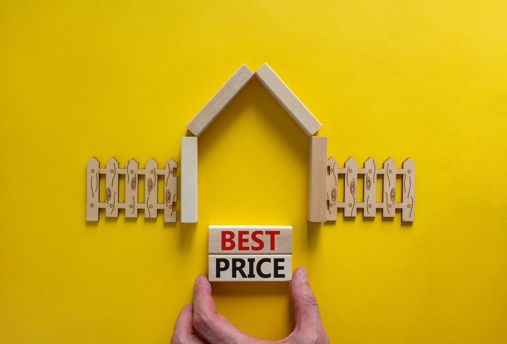 Wooden toy blocks shaped like a house with small picket fence sections and blocks reading Best Price