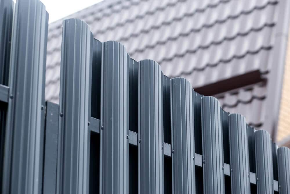 Rounded gray metal fence pickets in front of a tiled roof