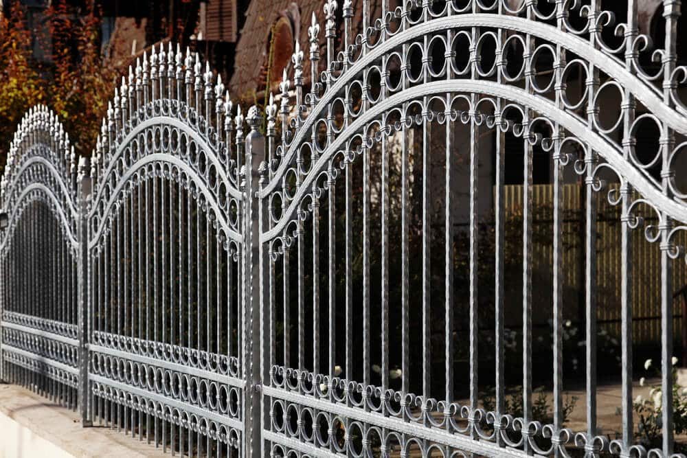 Silver ornamental iron fence with arched top rails, scrollwork rings, and pointed finials