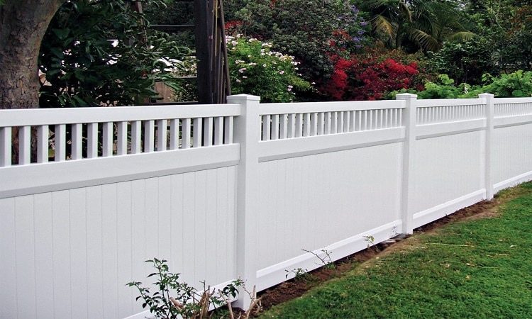A white vinyl fence with solid lower panels and an open picket top beside a green lawn